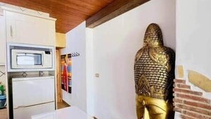 Een kamer met een witte kast, een magnetron en een gouden beeld.