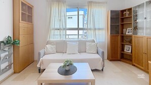 A living room with a sofa, a coffee table with a plant, and a wooden cabinet with shelves. - Apartment Chanquete in the center of Nerja - South Costa (Nerja)