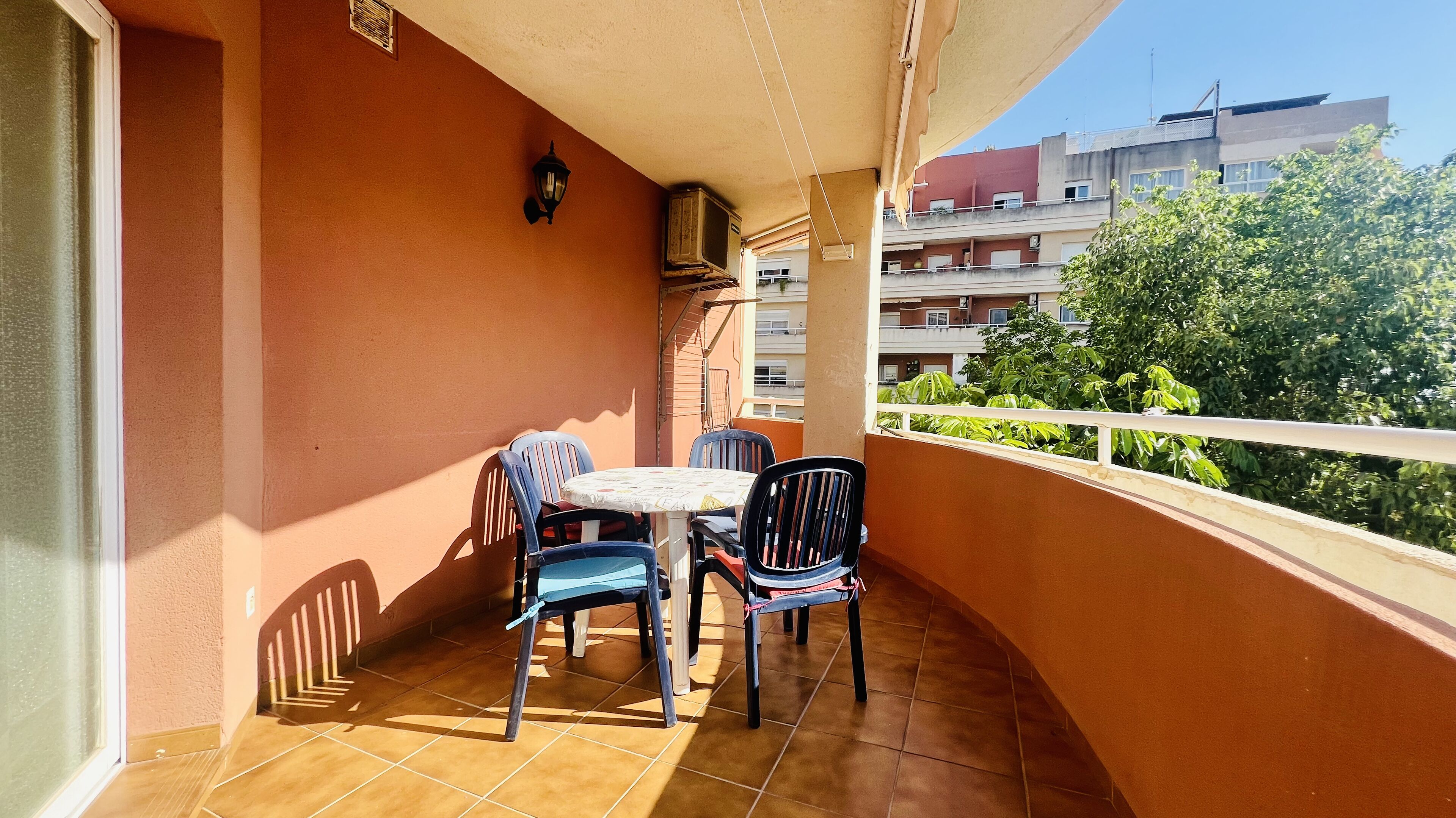 Een balkon met betegelde vloer, een tafeltje en twee stoelen.