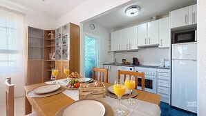 A compact kitchen with white cabinets, a microwave, and a refrigerator. - Apartment Chanquete in the center of Nerja - South Costa (Nerja)