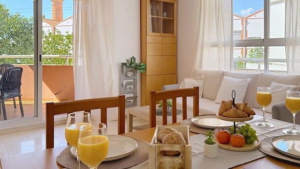 A breakfast setup with croissants, orange juice, and fruit on a table with a view of the outdoors. - Apartment Chanquete in the center of Nerja - South Costa (Nerja)