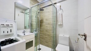 A modern bathroom with a glass-enclosed shower, a white sink, and a toilet.