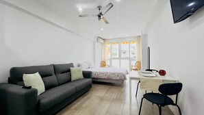 A room with a sofa, a bed, a desk, and a chair.