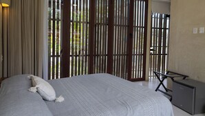 Een slaapkamer met een bed, een bureau en een raam met jaloezieën.