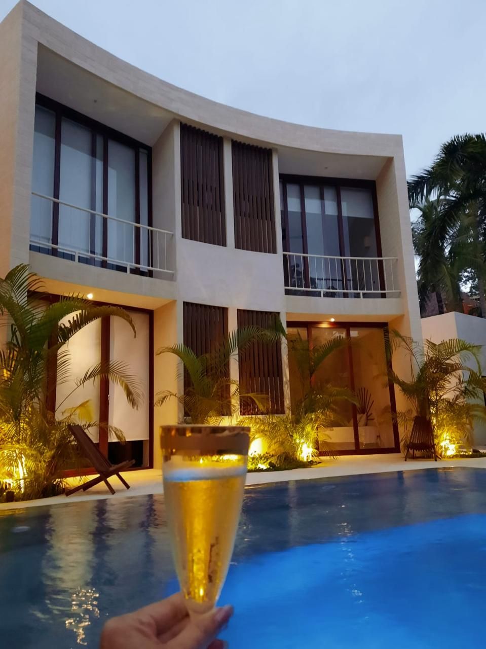 A modern building with a pool, featuring a curved balcony and large windows.