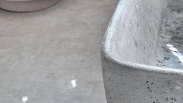 Una jardinera rectangular de hormigón con superficie texturizada, sobre una superficie plana.