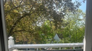 A balcony with a wicker sofa, patterned cushions, and a small table with glasses. - Cozy newly renovated condo, in Norwich, CT. 3 mins from Mohegan Sun Casino. (Norwich)