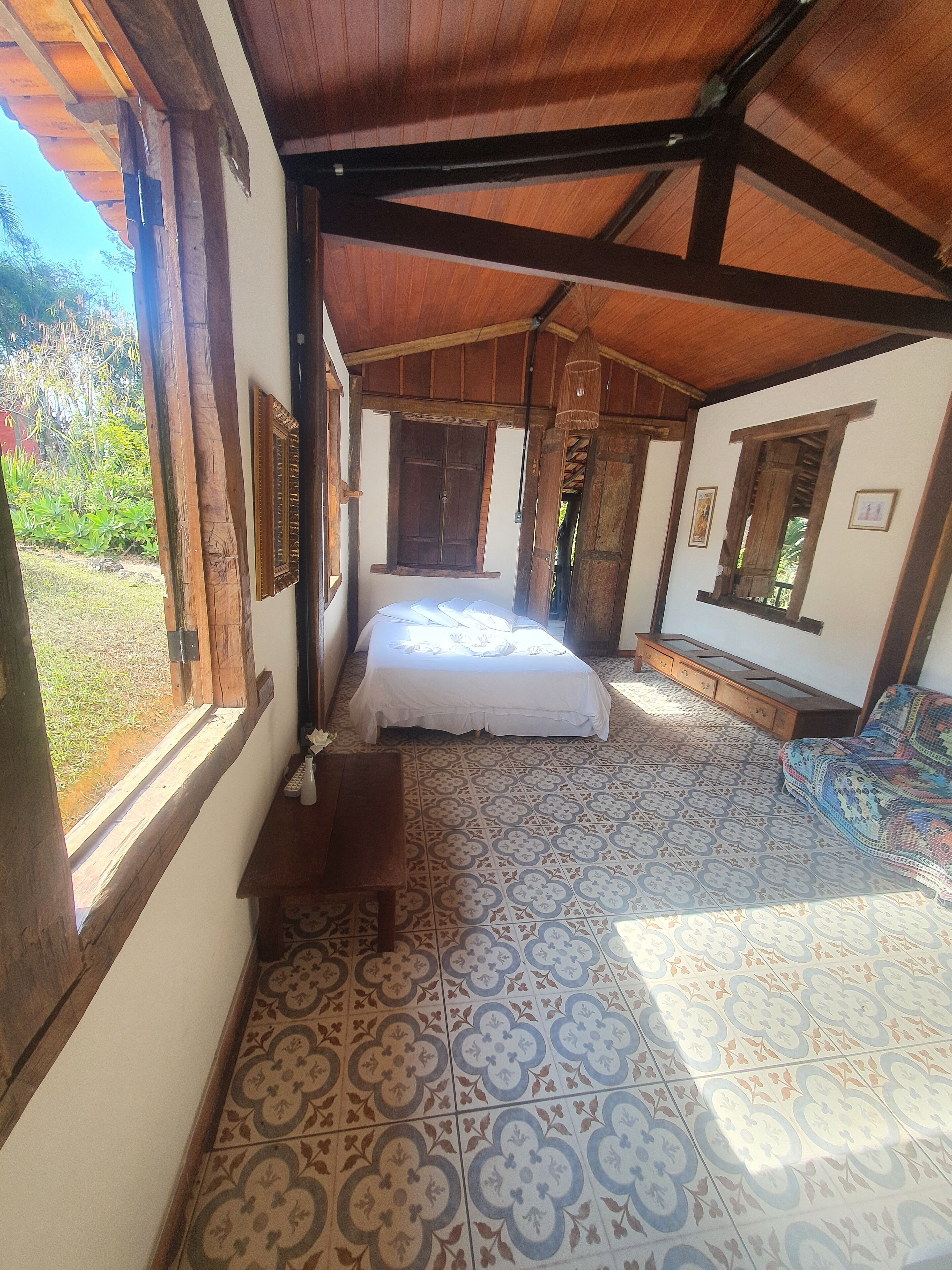 Una habitación con una cama, un banco de madera, una ventana y un suelo con diseño.