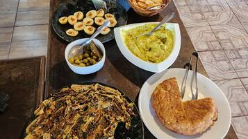 A buffet table with various dishes including a salad, beets, falafel, and a large platter of fried food.