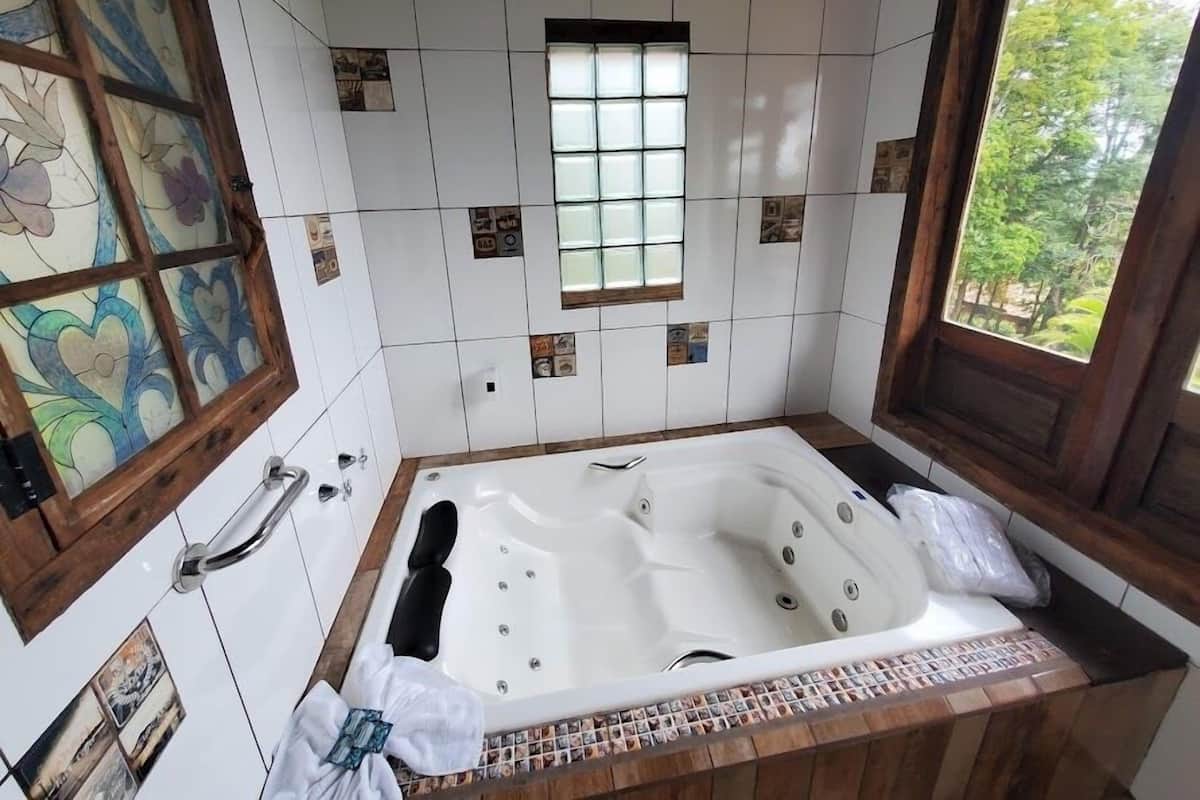 Ein Badezimmer mit einer großzügigen Badewanne, einem Fenster mit Blick ins Grüne und dekorativen Fliesen.