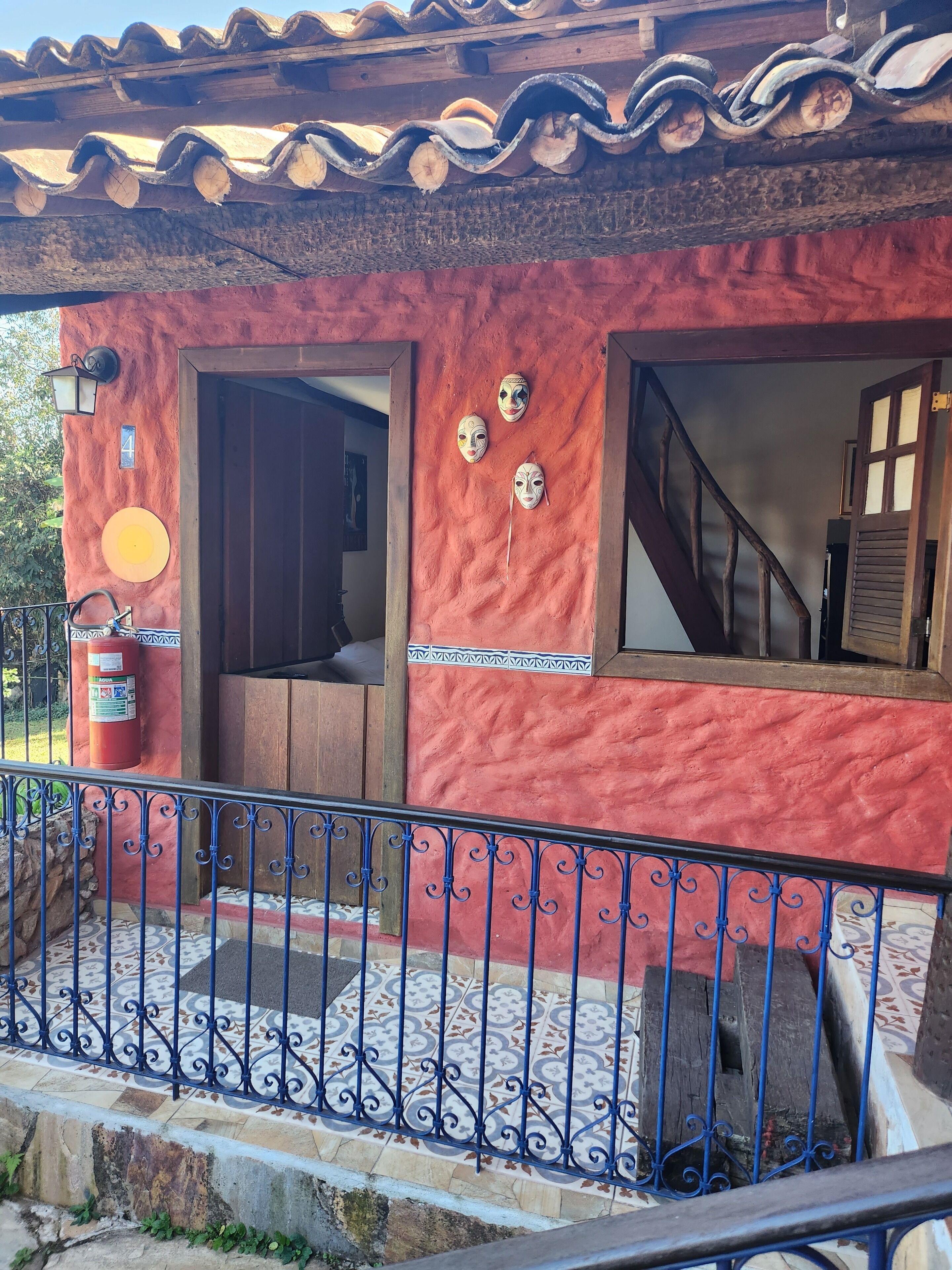A building with a red exterior, a wooden door, and a staircase leading inside.