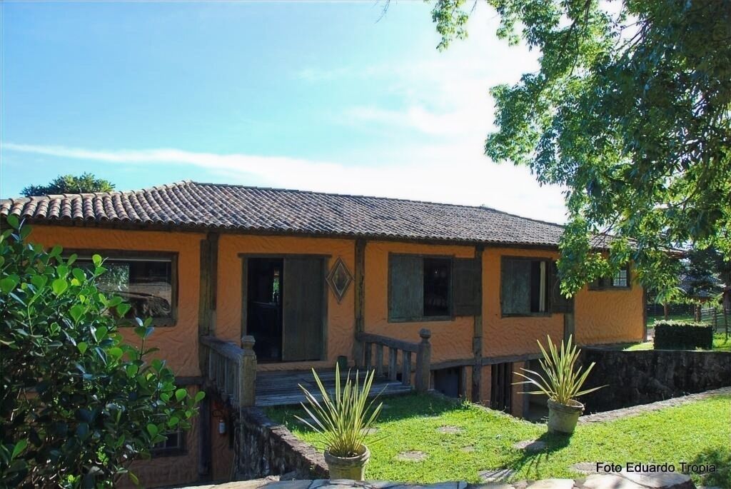 A two-story building with a tiled roof, a wooden porch, and a small garden with potted plants.