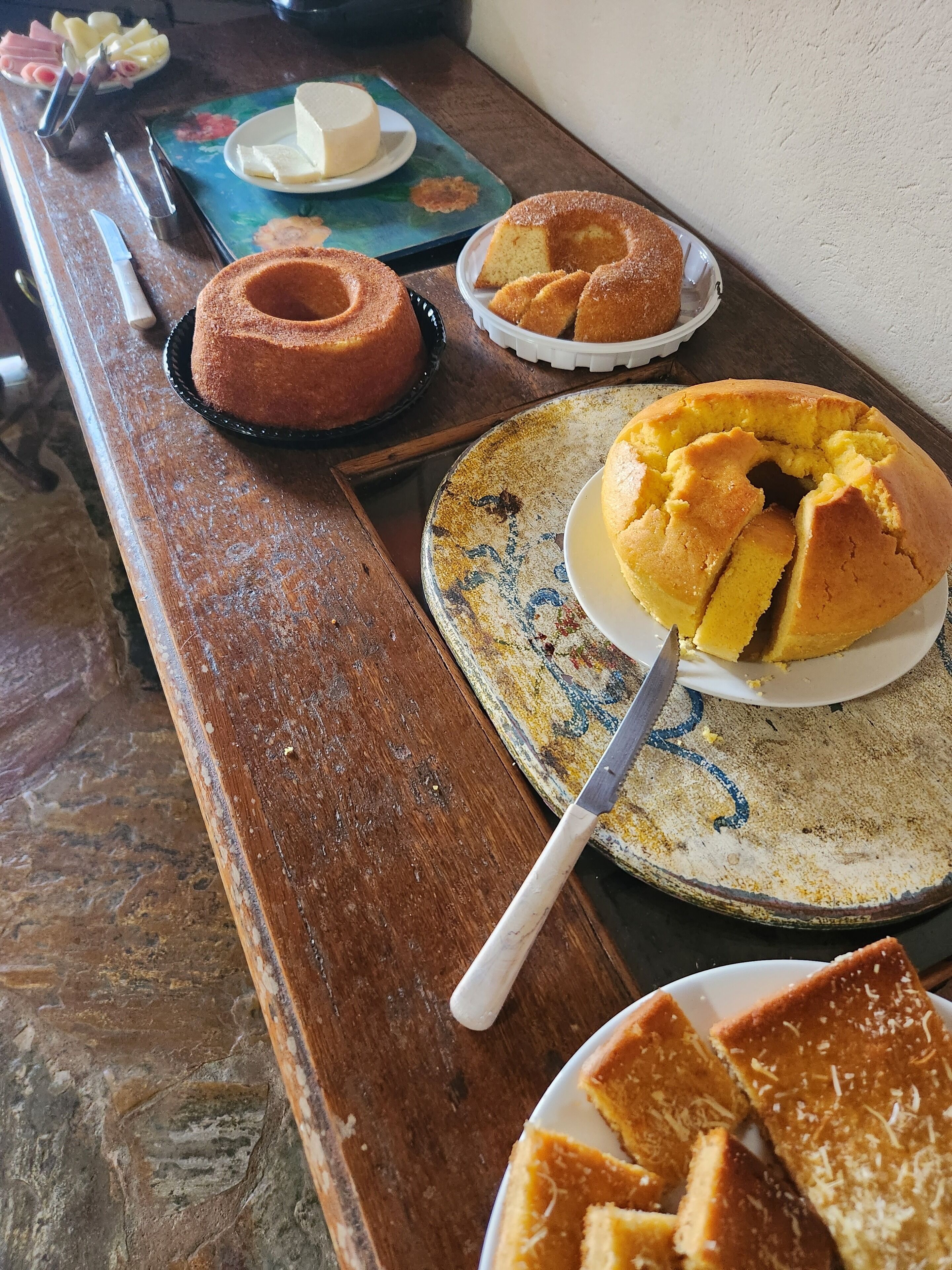 A wooden table with various cakes and a knife.