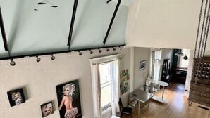 Amplia sala de estar con techo alto, piso de madera y una lámpara moderna.