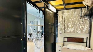 Un dormitorio con cama, una silla colgante y un armario.