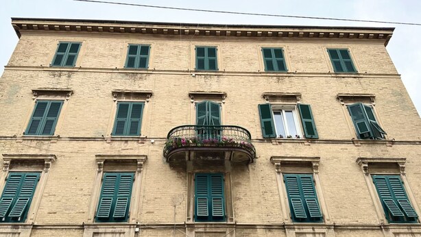 A multi-story building with a symmetrical facade, evenly spaced windows with shutters, and a central balcony with a wrought-iron railing. - A34 - Ancona, delightful two-room apartment in the centre (Ancona)
