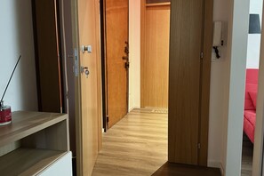 A hallway with wooden doors, a white wall with a phone, and a red object on a shelf. - A34 - Ancona, delightful two-room apartment in the centre (Ancona)