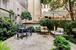 A patio with a table and chairs, a sofa, and an umbrella.
