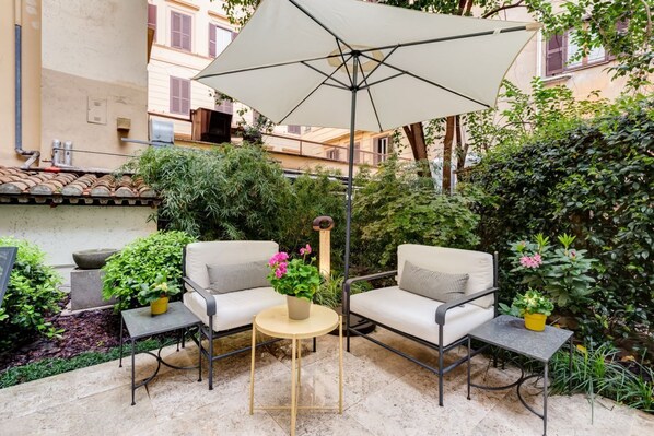 A patio with two chairs, a small round table, and a large umbrella.