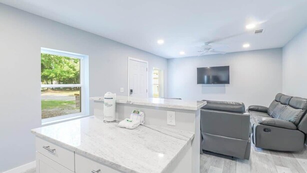 A modern kitchen with a marble countertop, a built-in oven, and a window with a view of greenery. - Cozy 2br/1ba Duplex Just Blocks From Downtown Biloxi, Beaches and Entertainment (Biloxi)