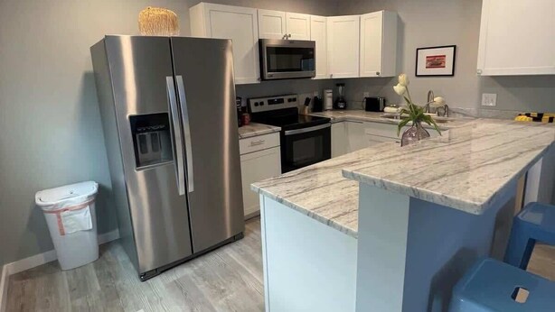Una cocina moderna con una isla central, electrodomésticos de acero inoxidable y armarios de colores claros.