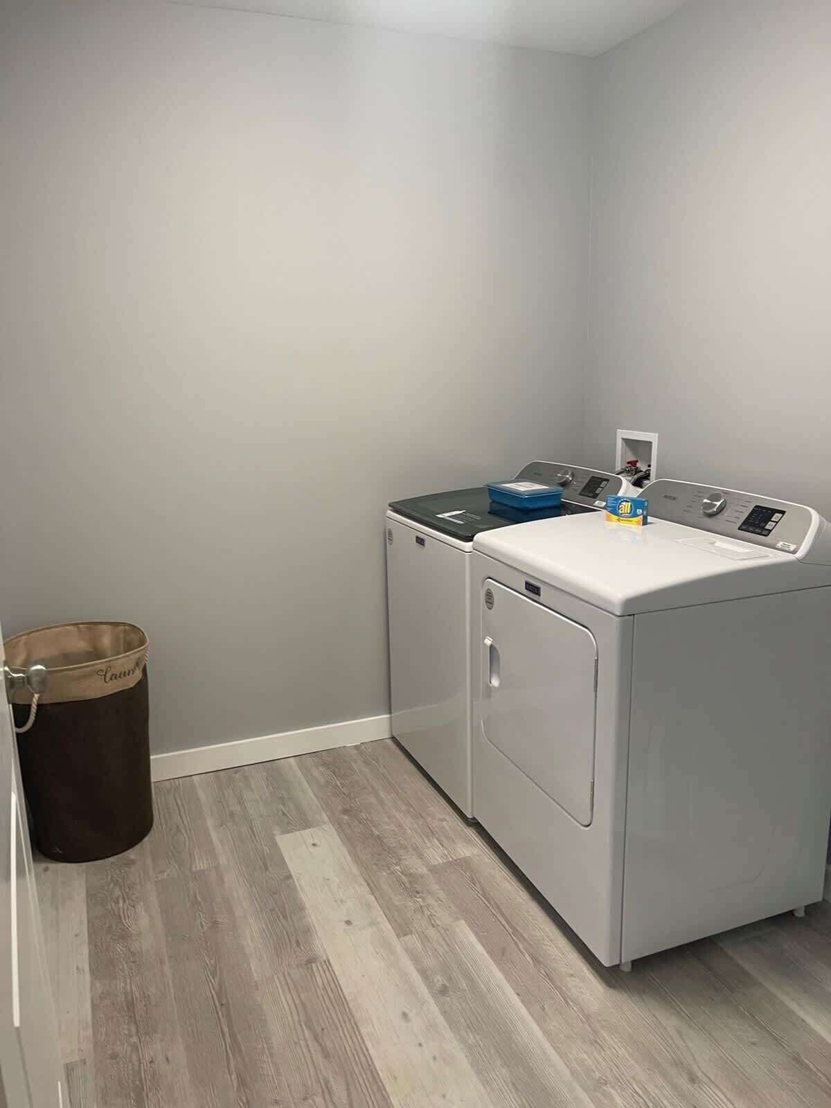 Une buanderie équipée d’un lave-linge, d’un sèche-linge et d’une poubelle.