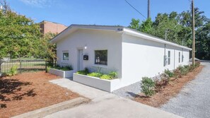 A single-story white building with a flat roof, a small porch with planters, and a visible mailbox. - Charming 2 Bedroom, 1 Bath Duplex Just Blocks From the Beautiful Beachfront (Biloxi)