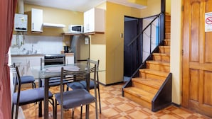 A compact kitchen with a dining area, a microwave, a stove, and a staircase. - Cabañas de la Costa (La Serena)