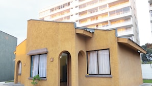 A two-story building with a yellow facade, multiple balconies, and a small entrance with a potted plant. - Cabañas de la Costa (La Serena)