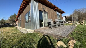 Ein modernes Haus mit Holzterrasse, großen Fenstern und einer Satellitenschüssel.