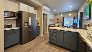 A modern kitchen with dark cabinets, stainless steel appliances, and a central island. - Sunflower Resort Susan Cabin is in the ultra-quiet Winthrop South community, with a 10 minute walk to downtown & on the pedestrian trail. (Winthrop)