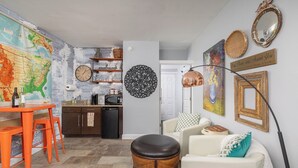 A living room with a dining area, a kitchen, and a wall with a map and decorative items. - Gypsy Soul, Free Parking and Steps to Downtown Charm (Eureka Springs)
