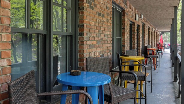 An outdoor seating area with brick walls, large windows, and wicker furniture. - Gypsy Soul, Free Parking and Steps to Downtown Charm (Eureka Springs)
