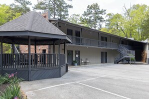 Un edificio con un área de estar al aire libre techada, una escalera y un estacionamiento.