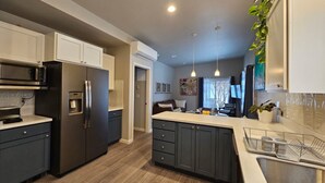 Une cuisine moderne avec des meubles de couleur sombre, des appareils électroménagers en acier inoxydable et un plancher en bois.