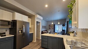 A modern kitchen with dark cabinetry, stainless steel appliances, and a central island.