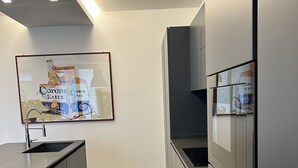 A modern kitchen with a large island, built-in oven, and a framed Corona Extra beer advertisement. - Entire Apartment at the foot of Valpolicella! (Pescantina)