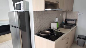 A compact kitchen with a refrigerator, stove, microwave, and a small sink.