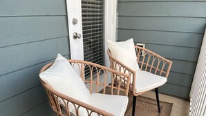Two wicker chairs with white cushions on a porch with a door and a window. - Belmont 2BR - Minutes to CaroMont | 14+ Nights (Belmont)