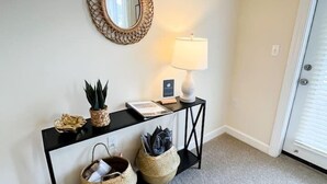 A room with a console table, a mirror, a lamp, and two baskets. - Belmont 2BR - Minutes to CaroMont | 14+ Nights (Belmont)