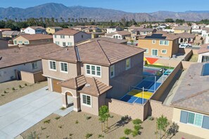 Un quartier résidentiel avec des maisons, une aire de jeux et des montagnes en arrière-plan.