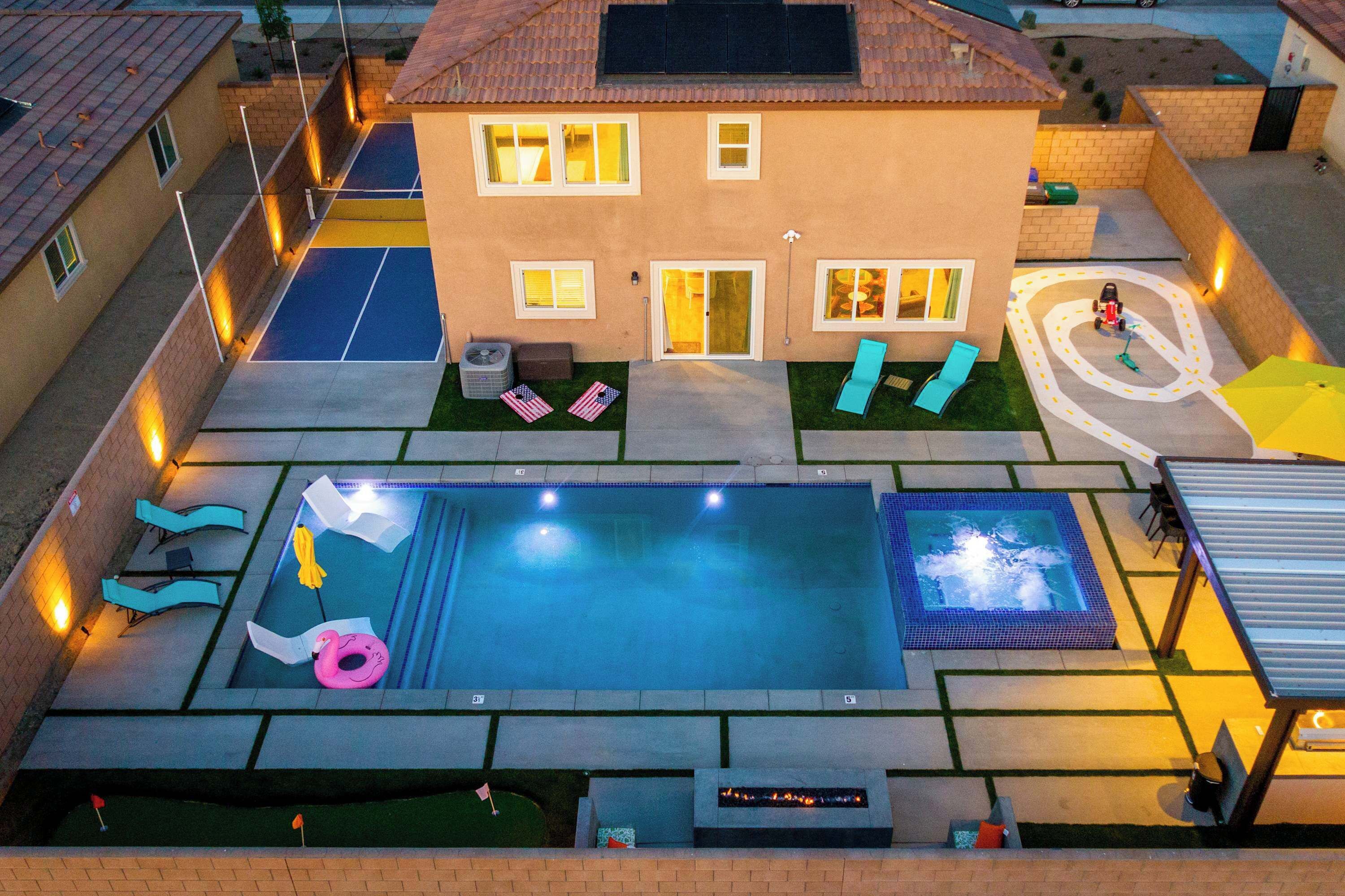 A residential backyard with a swimming pool, a hot tub, and a children's play area.