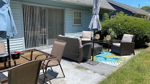 Un patio con mobiliario exterior, incluyendo sillas y una mesa, y una sombrilla.