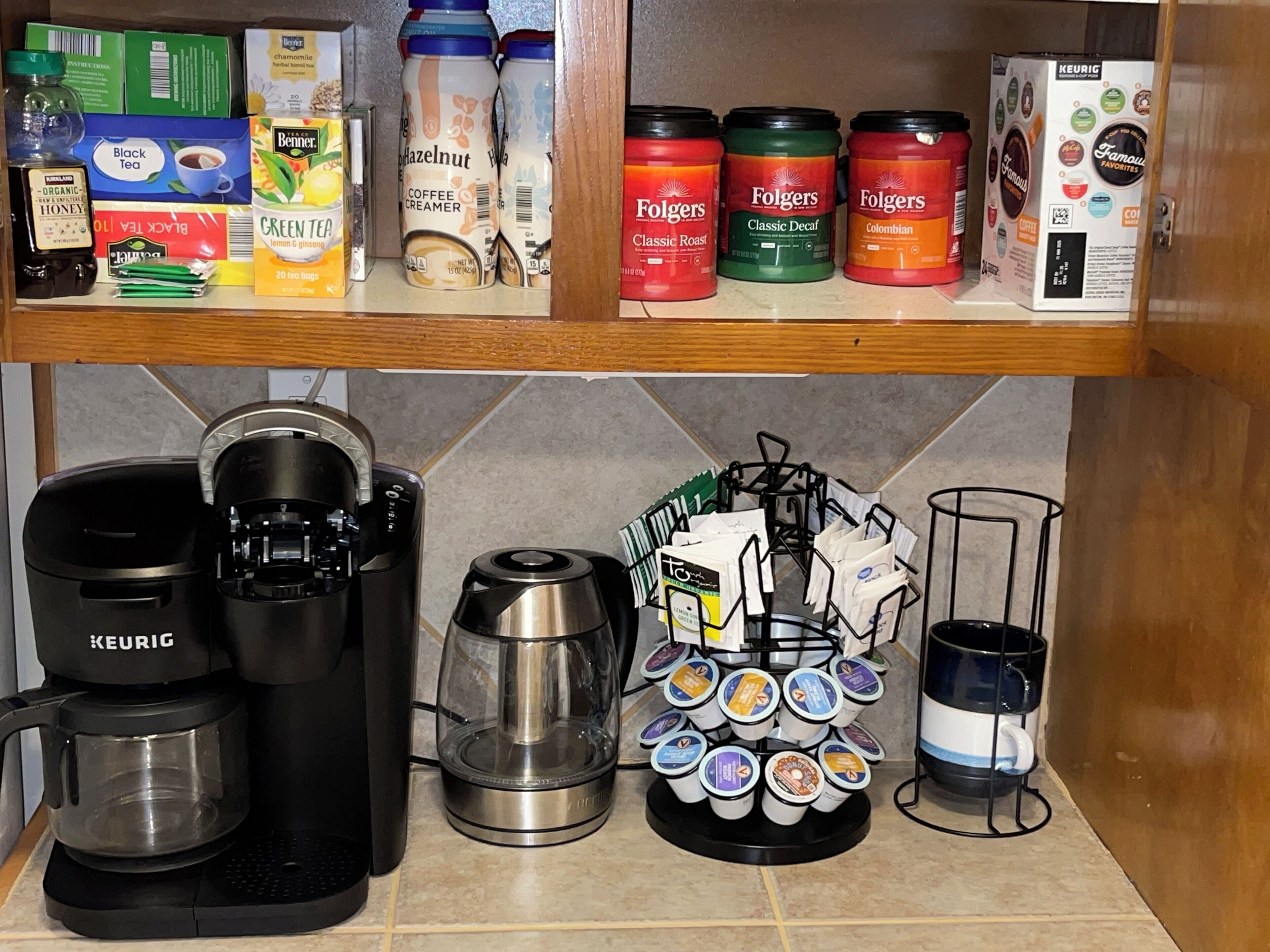 A kitchen with a Keurig coffee maker, a coffee pot, a coffee grinder, and a mug rack with coffee pods.