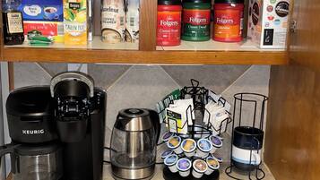 A kitchen with a Keurig coffee maker, a coffee pot, a coffee grinder, and a mug rack with coffee pods.