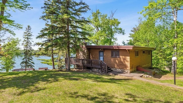 A cabin by a lake with a deck and a small porch.