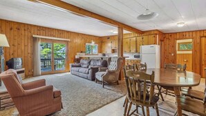 A spacious living area with a fireplace, a dining table with chairs, and a kitchen area with cabinets and a refrigerator.