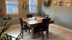 A dining area with a wooden table, four chairs, a chandelier, and framed posters on the wall. - TC West Side Condo, Central Location, Spacious, Dog Friendly! (Traverse City)