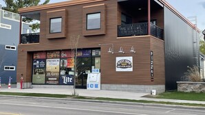 A two-story building with a sign for 'West Side Beverage' and 'Pizza' on the ground floor. - TC West Side Condo, Central Location, Spacious, Dog Friendly! (Traverse City)