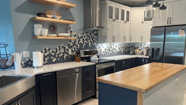 A modern kitchen with stainless steel appliances, a wooden countertop, and a blue backsplash. - TC West Side Condo, Central Location, Spacious, Dog Friendly! (Traverse City)